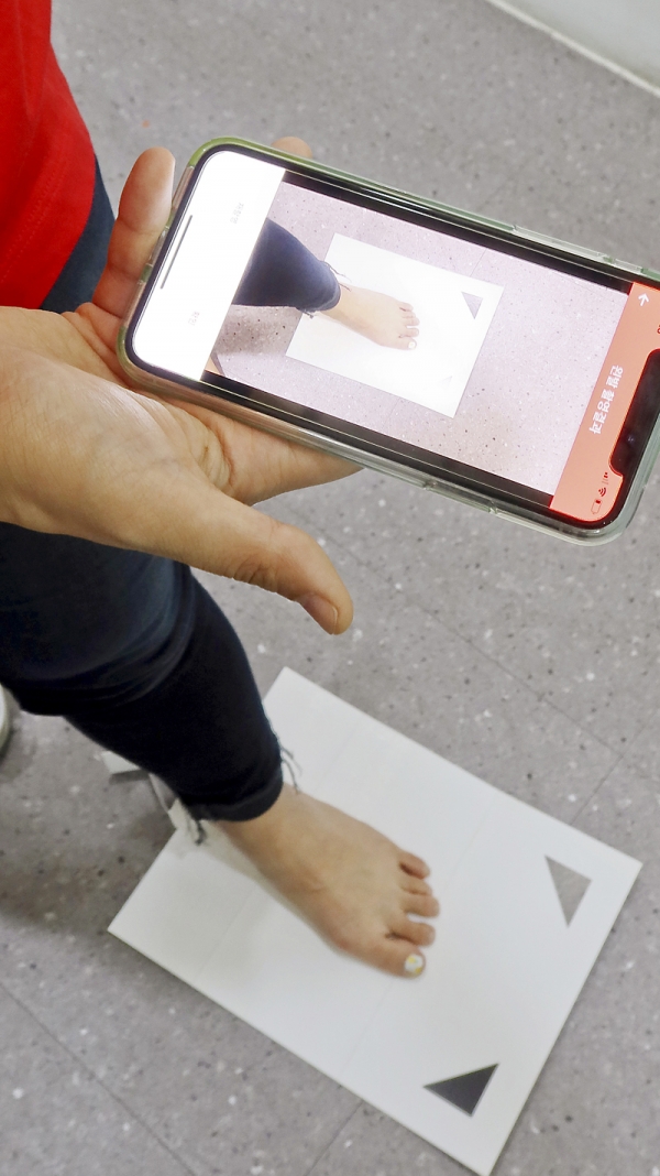 펄핏은 발과 신발 데이터를 활용해 사이즈를 추천하는 AI를 개발했다. 고객은 매장에 가지 않고 본인 발에 맞는 신발을 온라인으로 살 수 있다. 고객이 종이 키트 위에 발을 맞추고 스마트폰으로 발사이즈를 측정하고 있다. 